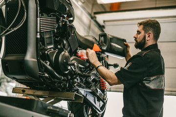 Motorcycle mechanic replacing and pouring fresh oil into engine at maintenance repair service station. Portrait of an auto mechanic putting oil in a car engine.