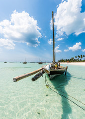 wooden boat anchored on the African shore in clear ocean water - obrazy, fototapety, plakaty
