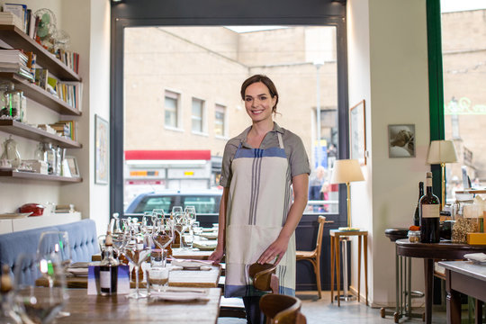 Happy young waitress inside cool restaurant