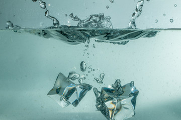 Eiswürfel tauchen in Wasser ein