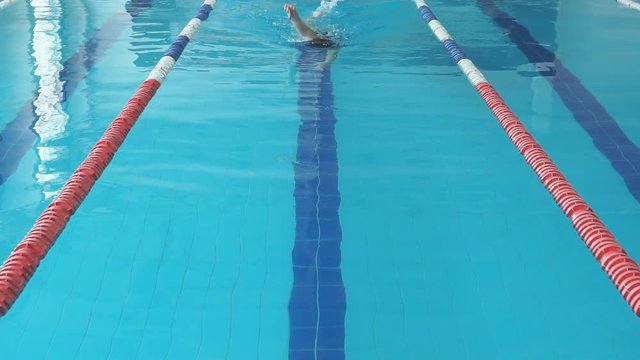 Fit swimmer girl jumping and cheering in swimming pool in slow motion
