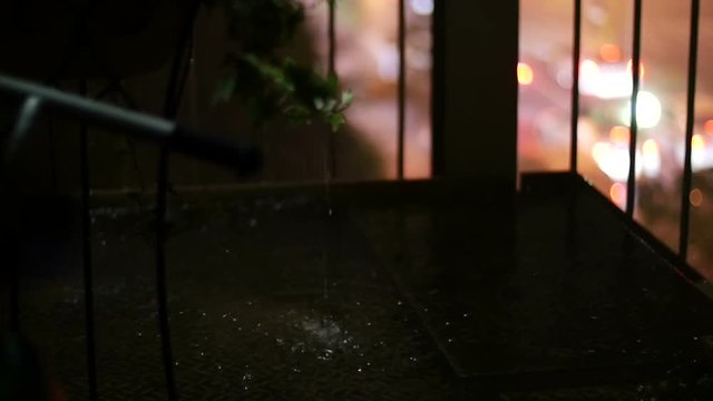 (slow motion) Pouring raindrops on stairs and out of focus traffic illumination in the background.