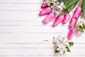 Apple tree flowers and pink tulips  on white wooden background.