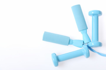 Composition placed neatly holding plastic lightweight dumbbells and skipping rope