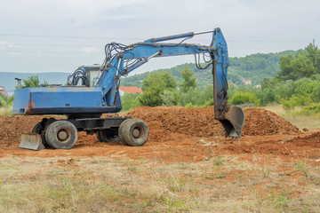 old Excavator digger at red earth ground