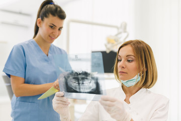 woman dentist with her assistant examine dental x-ray