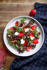 Strawberry salad with balsamic vinegar, fennel, cream cheese, walnuts and greens. Easy summer food concept. Wooden background, copy space.