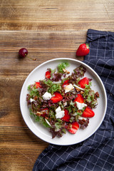 Strawberry salad with balsamic vinegar, fennel, cream cheese, walnuts and greens. Easy summer food concept. Wooden background, copy space.