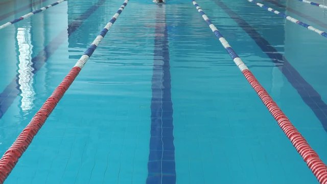 Young girl in goggles and cap swimming backstroke