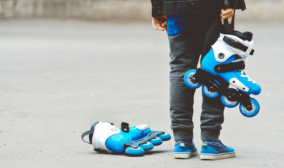 Toned baner little beautiful boy with roller skates in his hands