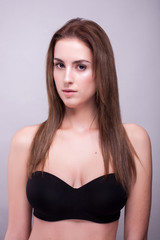 Gorgeous woman in bra with natural make up on gray background in studio photo. Beauty and fashion.
