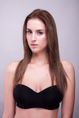 Fototapeta premium Gorgeous woman in bra with natural make up on gray background in studio photo. Beauty and fashion.