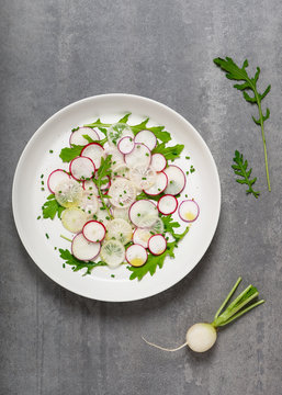 Plate of spring vegetables salad with colorful radishes, arugula and chives. Healthy food concept. Top view.
