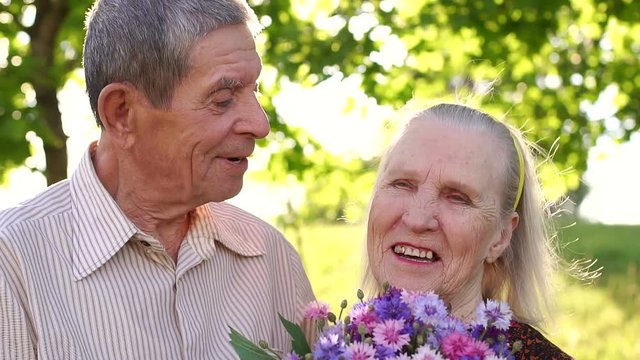 Close-up of a grandfather of eighty years kisses his happy wife in the Park in the summer.