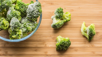 Frosen broccoli in a glass bowl on a wooden surface