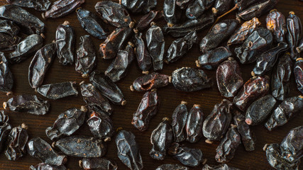 Dried barberry scattered on a dark wooden surface close-up
