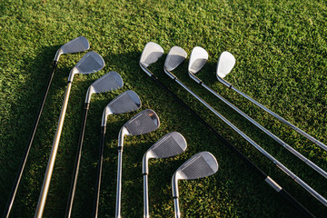 Shiny golf clubs arranged on the green grassy field