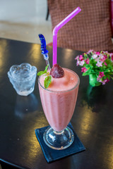 A glass of strawberry smoothie on a wooden background