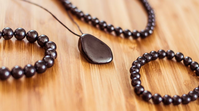 Shungite jewellery lies on a wooden surface