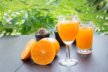 Glass of freshly pressed orange juice with sliced orange half on wooden table