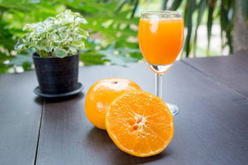 Glass of freshly pressed orange juice with sliced orange half on wooden table