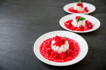 Jelly Panna cotta with fruit syrup and tasty berries in a plates on a dark table. Flat lay. Top view. Traditional Italian dessert.