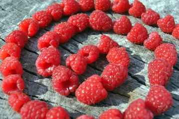 Fresh red natural raspberry swirl shapes, on old cracked wooden background, closeup