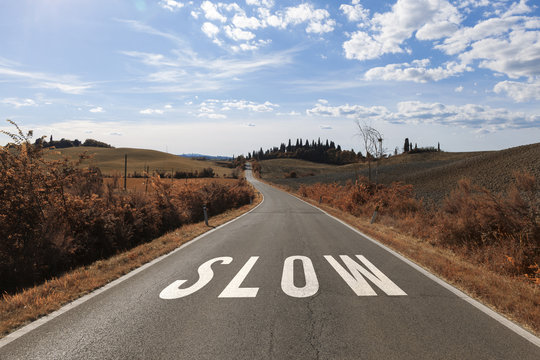 Concept drive slow message on the sunny summer asphalt country road. Conceptual slowly driving alert background.