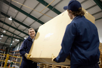 Two workers carrying large box