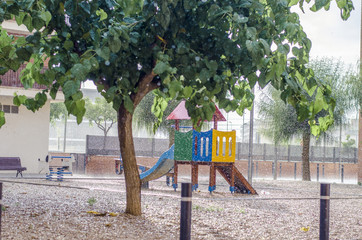 It is raining in a children's playground, rain drops falling