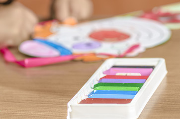 Cute little girl painting with crayon on a home interior background