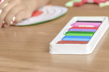 Cute little girl painting with crayon on a home interior background
