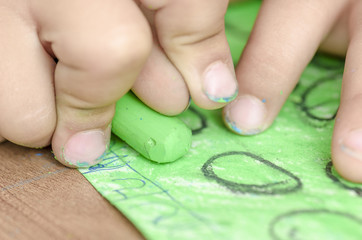 Cute little girl painting with crayon on a home interior background