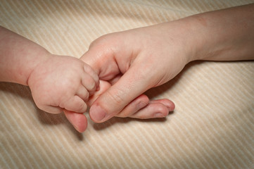 Newborn holds mum's finger
