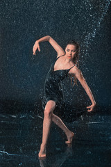 Fototapeta premium The young beautiful modern dancer dancing under water drops
