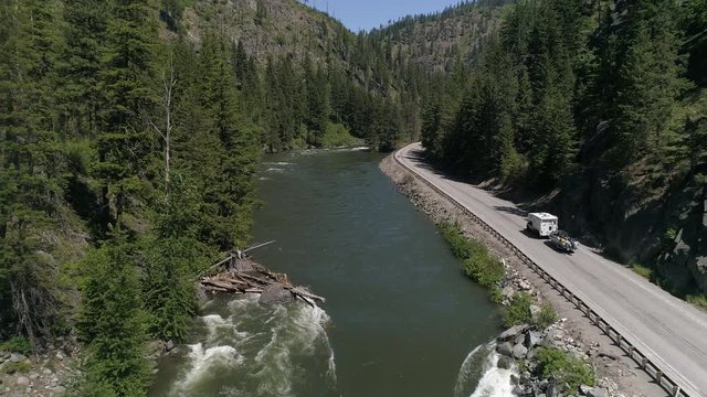 Drone Flying Up Pacific Northwest River with Camper RV Towing Boat on Mountain Highway