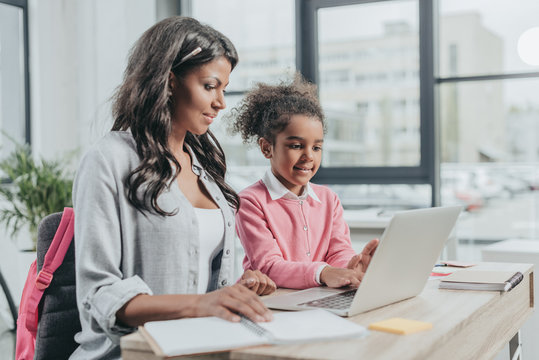 Little Daughter Helping Mother Working On Laptop At Business Office, Work And Life Balance Concept