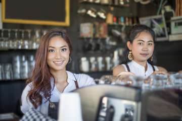 Fototapeta premium Asian women Barista smiling and using coffee machine in coffee shop counter - Working woman small business owner food and drink cafe concept