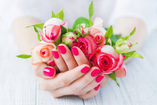 Cupped hands with pink manicured fingernails holding delicate roses