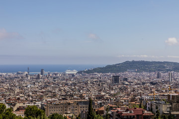 Barcelona skyline with ship at port sea and Montjüic hill from park Güell