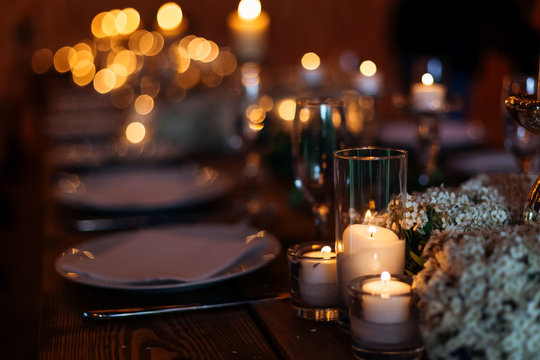 Candles on wedding table set on a beautiful lit background. Forget-me-not flowers lit by candles on wooden table