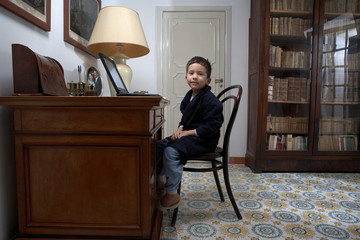 Boy sitting at desk using laptop