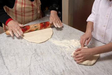Senior woman and girl rolling pastry