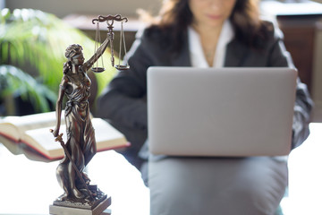 Lawyer office. Statue of Justice with scales and lawyer working on a laptop. Legal law, advice and justice concept