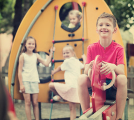 Fototapeta na wymiar Smiling boy sitting on swing on children's playground