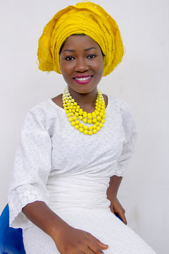 an African lady with head tie, bead necklace, beautiful makeup and smiling
