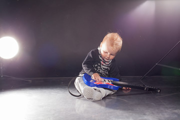 little boy musician playing rock music on the guitar