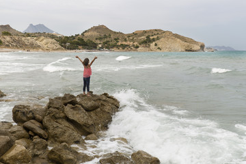 Fototapeta na wymiar Girl with arms raised on the rocks