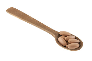 Tablets in a wooden spoon isolated on a white background
