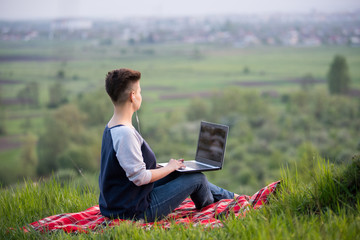 Rearview shot of a woman sitting on top of a hill working on her laptop copyspace nature travelling relaxing recreation studying working education online internet computer technology